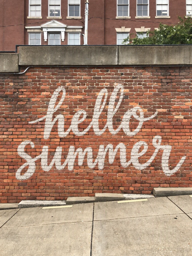 The same wall with hello summer painted across it in white brush script
