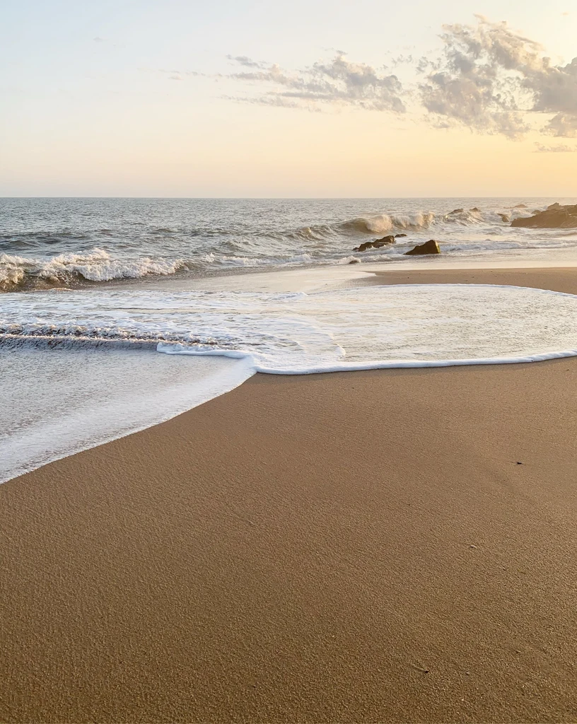 Golden-hour beach with smooth wet sand and a line of foam