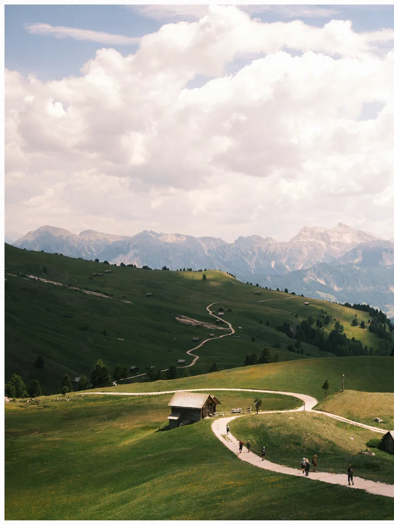 The same Dolomites landscape with the caption removed and the clouds filled in where the text was; the hut, path, hikers and mountains are unchanged.